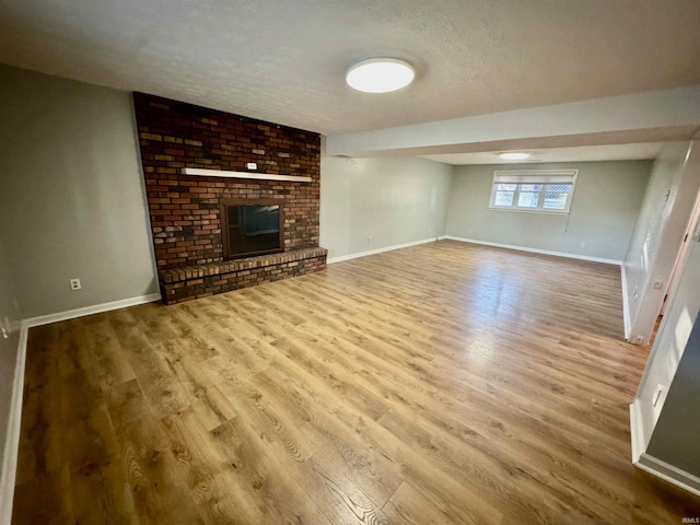 unfurnished living room featuring a fireplace, light wood-type flooring, and a textured ceiling