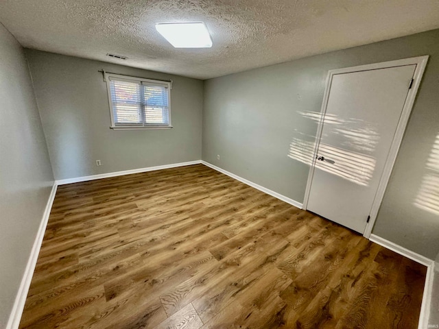 spare room featuring hardwood / wood-style flooring and a textured ceiling