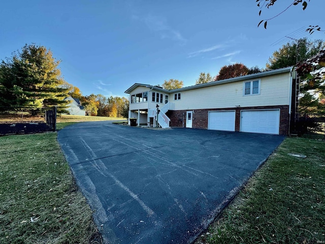 view of front of property featuring a garage, a front lawn, aphalt driveway, and stairway