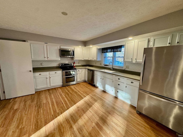 kitchen with white cabinetry, sink, light hardwood / wood-style flooring, a textured ceiling, and appliances with stainless steel finishes