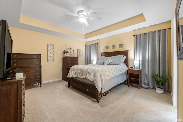 bedroom with light carpet, a tray ceiling, and ceiling fan