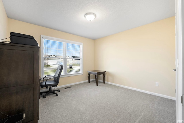 carpeted office space featuring a textured ceiling