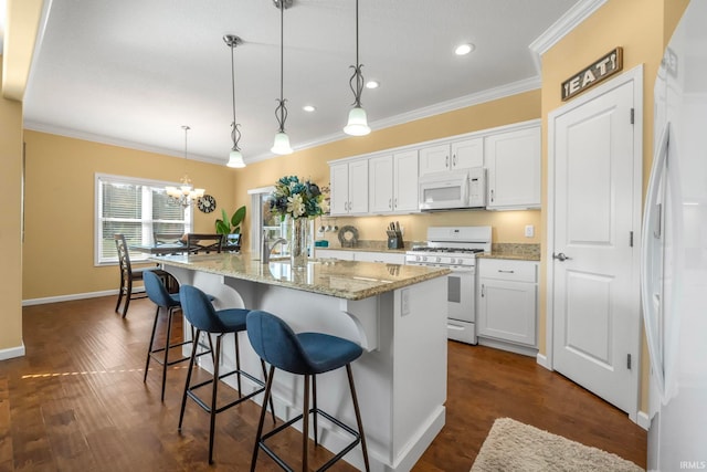 kitchen featuring white cabinetry, white appliances, hanging light fixtures, and a kitchen island with sink