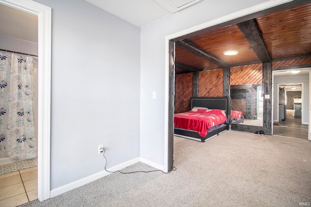 bedroom featuring wood ceiling, beamed ceiling, wooden walls, and light colored carpet