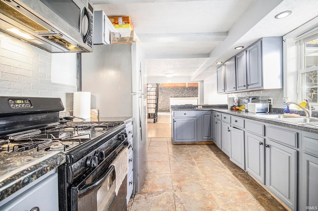 kitchen featuring gray cabinetry, decorative backsplash, black gas range oven, and sink