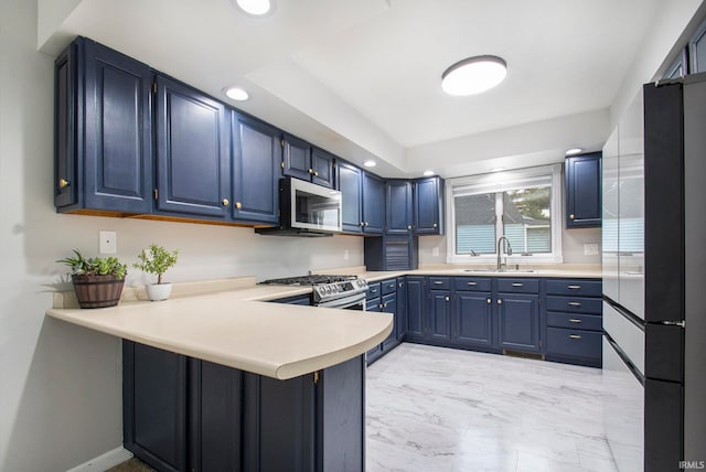 kitchen featuring appliances with stainless steel finishes, sink, kitchen peninsula, and blue cabinets