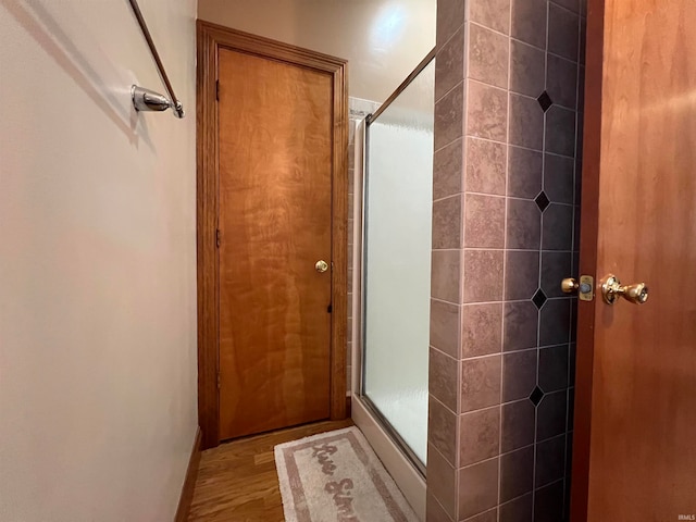 bathroom with a shower with door and hardwood / wood-style floors