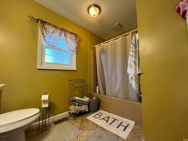 bathroom featuring toilet, tile patterned floors, shower / bath combo with shower curtain, and a textured ceiling