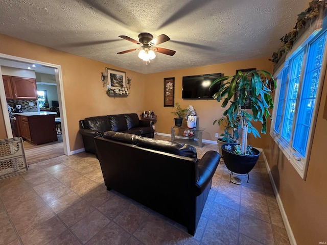 living room with a wealth of natural light, a textured ceiling, light tile patterned floors, and ceiling fan