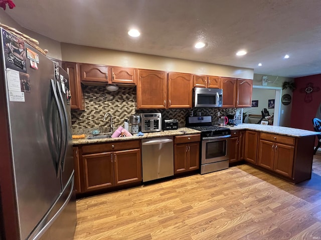 kitchen featuring decorative backsplash, appliances with stainless steel finishes, kitchen peninsula, and light hardwood / wood-style floors