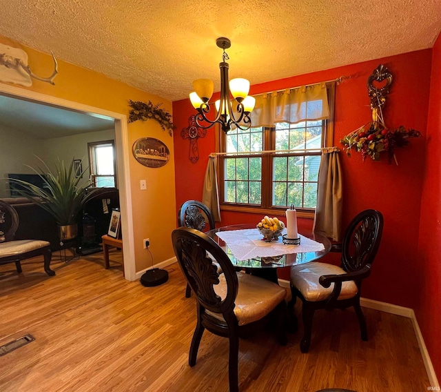 dining space featuring hardwood / wood-style floors, a textured ceiling, and a chandelier