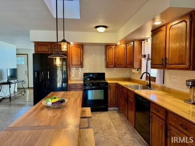 kitchen with decorative backsplash, butcher block counters, hanging light fixtures, sink, and black appliances