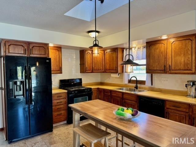 kitchen featuring tasteful backsplash, black appliances, sink, and hanging light fixtures