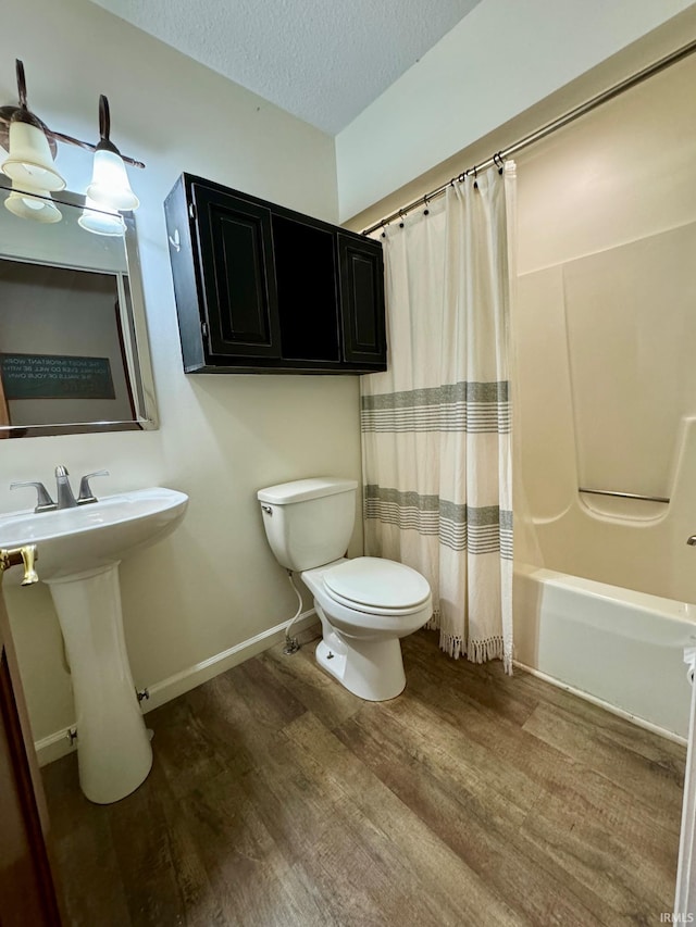 bathroom with toilet, hardwood / wood-style flooring, a textured ceiling, and shower / bath combo