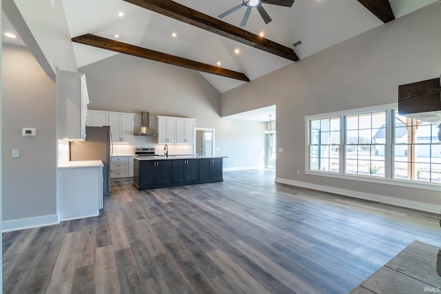 kitchen featuring white cabinets, a spacious island, hardwood / wood-style flooring, high vaulted ceiling, and wall chimney exhaust hood