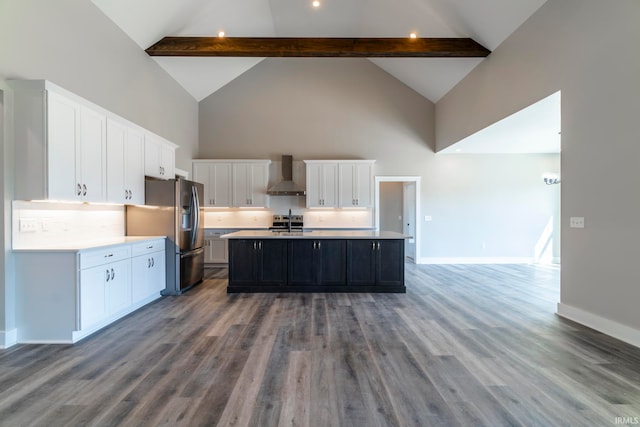 kitchen featuring wall chimney range hood, a center island with sink, white cabinetry, hardwood / wood-style flooring, and beamed ceiling