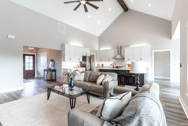 living room with dark hardwood / wood-style floors, beam ceiling, sink, high vaulted ceiling, and ceiling fan