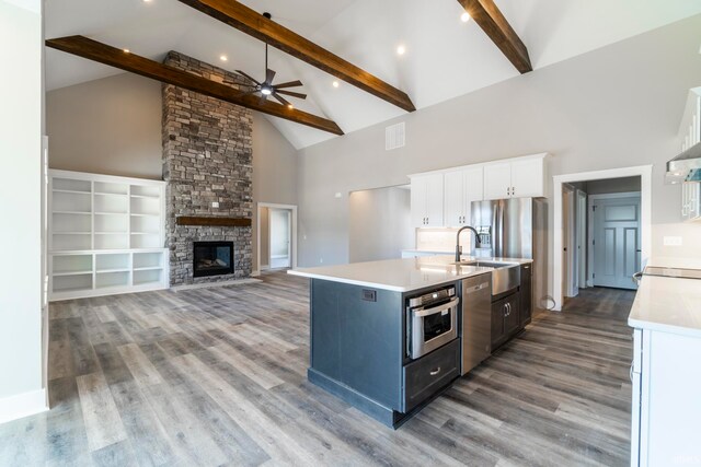 kitchen with white cabinets, a center island with sink, high vaulted ceiling, beamed ceiling, and stainless steel appliances