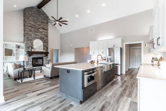 kitchen featuring white cabinetry, high vaulted ceiling, beamed ceiling, and a kitchen island with sink