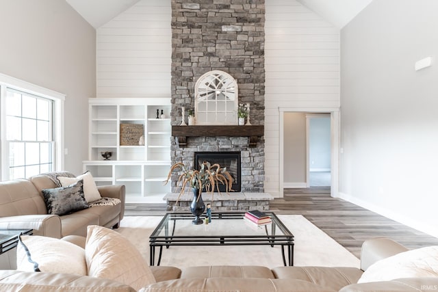 living room with high vaulted ceiling, wood-type flooring, and a stone fireplace