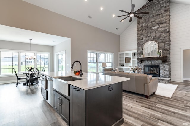 kitchen with plenty of natural light, high vaulted ceiling, decorative light fixtures, and an island with sink