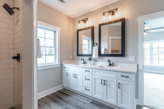 bathroom with vanity, hardwood / wood-style floors, a tile shower, and ceiling fan