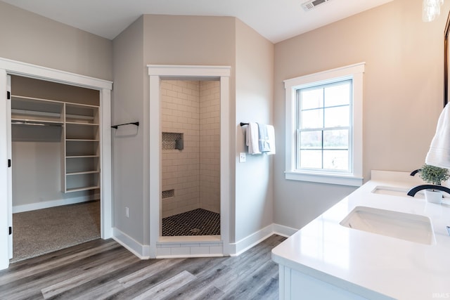 bathroom with a tile shower, wood-type flooring, and vanity