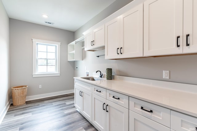 kitchen with sink, white cabinetry, and light hardwood / wood-style flooring