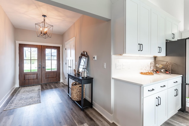 foyer entrance with an inviting chandelier, french doors, and dark wood-type flooring