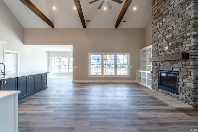 unfurnished living room featuring beam ceiling, ceiling fan, high vaulted ceiling, dark wood-type flooring, and a fireplace