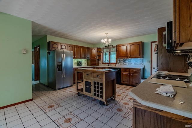 kitchen with a kitchen island, hanging light fixtures, stainless steel appliances, sink, and a chandelier