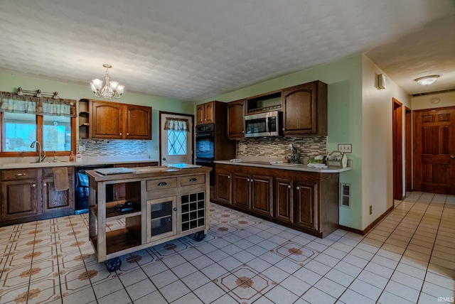 kitchen featuring black dishwasher, a notable chandelier, decorative light fixtures, and plenty of natural light