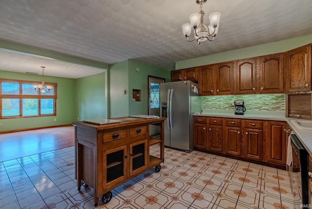 kitchen with stainless steel fridge, backsplash, an inviting chandelier, a textured ceiling, and pendant lighting