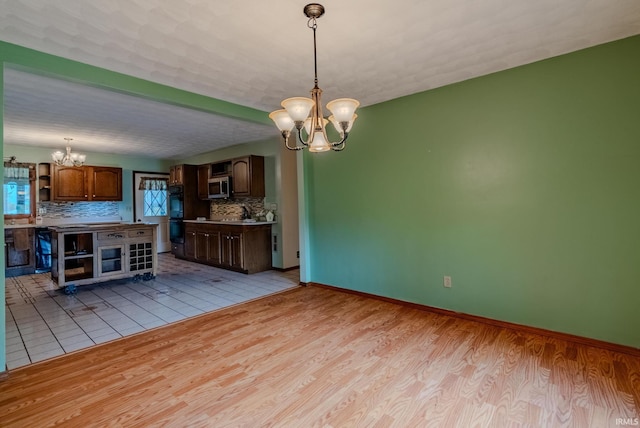 kitchen featuring light hardwood / wood-style floors, tasteful backsplash, a chandelier, and pendant lighting