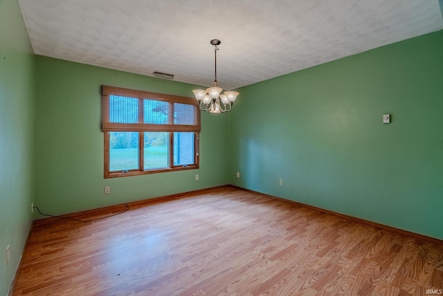 spare room with a chandelier and light hardwood / wood-style flooring