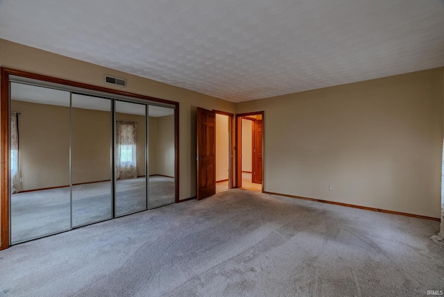 unfurnished bedroom with light carpet and a closet