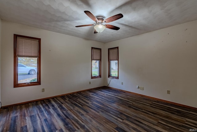 empty room featuring dark wood-type flooring, ceiling fan, a textured ceiling, and a wealth of natural light