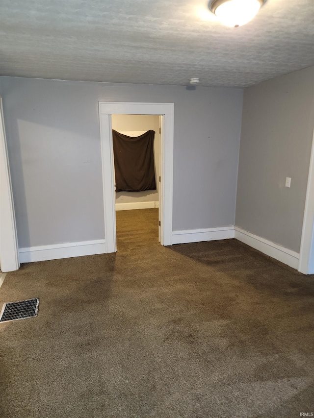 carpeted empty room with a textured ceiling