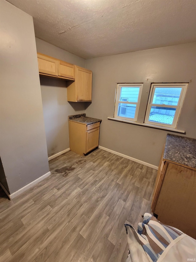 kitchen with a textured ceiling, light wood-type flooring, and light brown cabinets