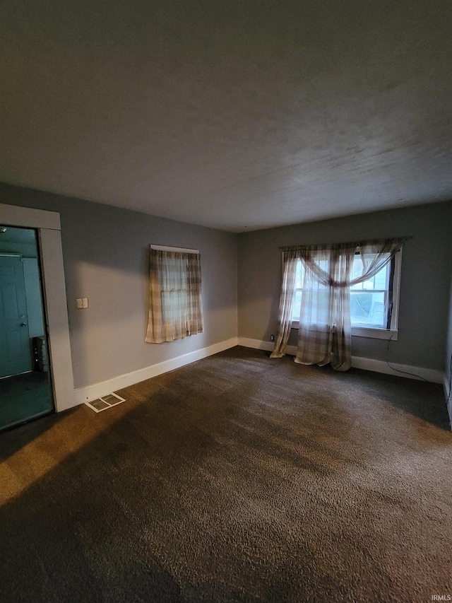 empty room featuring a textured ceiling and dark carpet