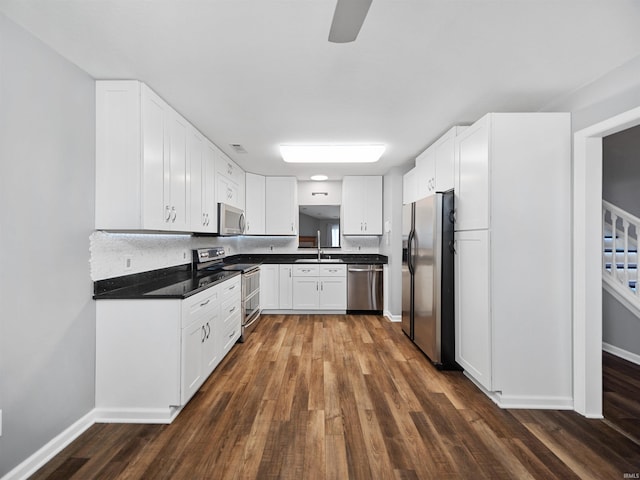 kitchen with appliances with stainless steel finishes, dark hardwood / wood-style floors, white cabinets, and sink