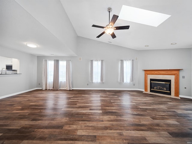 unfurnished living room with lofted ceiling with skylight, dark wood-type flooring, and ceiling fan