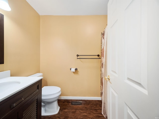 bathroom with toilet, vanity, and wood-type flooring