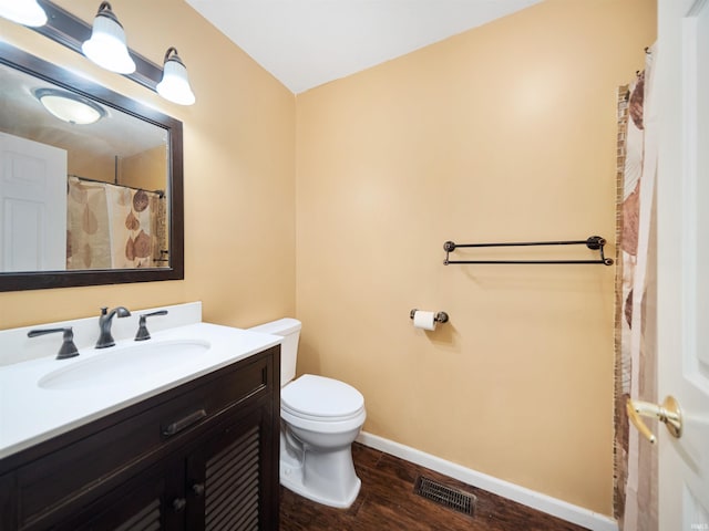 bathroom with toilet, vanity, and wood-type flooring