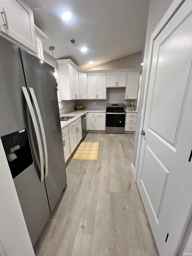 kitchen featuring lofted ceiling, appliances with stainless steel finishes, pendant lighting, and white cabinetry