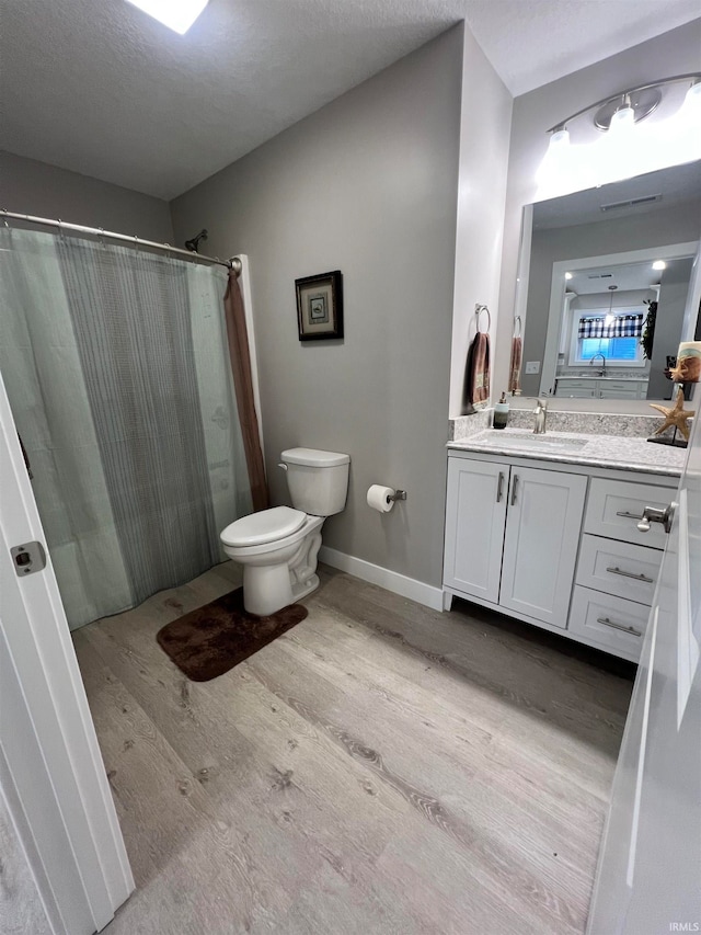 bathroom featuring a textured ceiling, wood-type flooring, toilet, vanity, and a shower with curtain