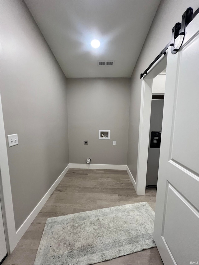 laundry room with washer hookup, a barn door, hardwood / wood-style flooring, gas dryer hookup, and electric dryer hookup