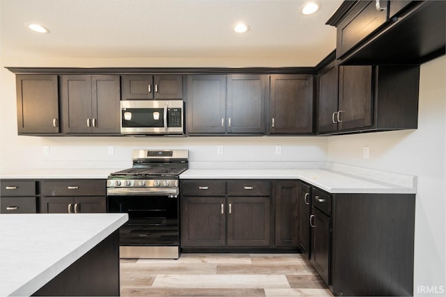 kitchen with appliances with stainless steel finishes, dark brown cabinets, and light hardwood / wood-style floors