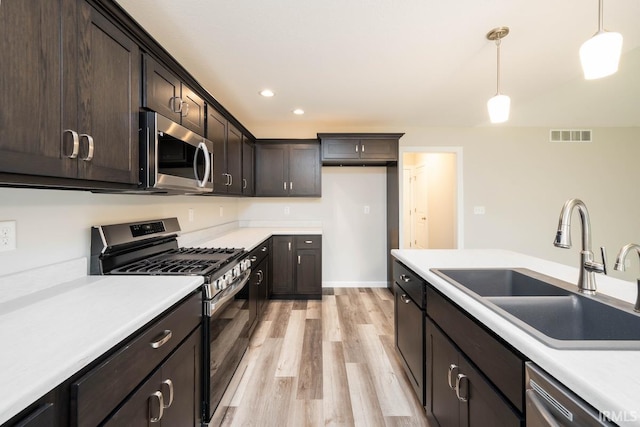 kitchen featuring dark brown cabinets, light hardwood / wood-style flooring, decorative light fixtures, and stainless steel appliances