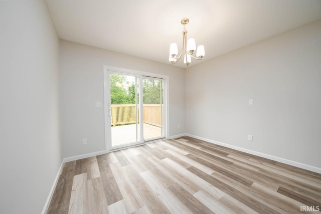 spare room featuring light hardwood / wood-style floors and a chandelier